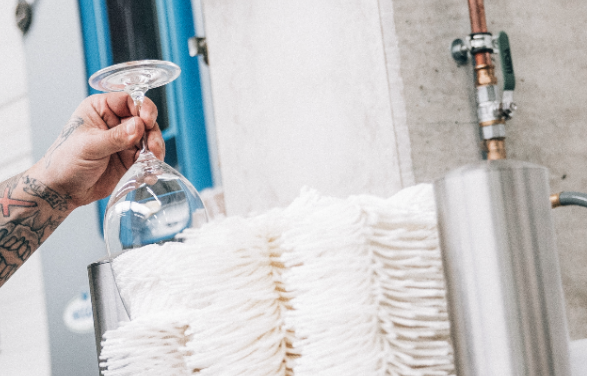 Eine Hand hält ein Weinglas in die Polierbürste