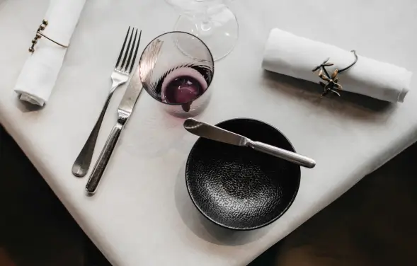 Ordentlich arrangiertes Besteck und Teller auf einem gedeckten Tisch.