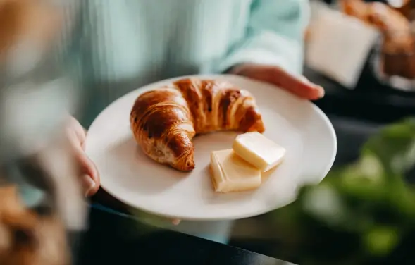 Frisches Croissant mit Butter auf einem Frühstücksteller