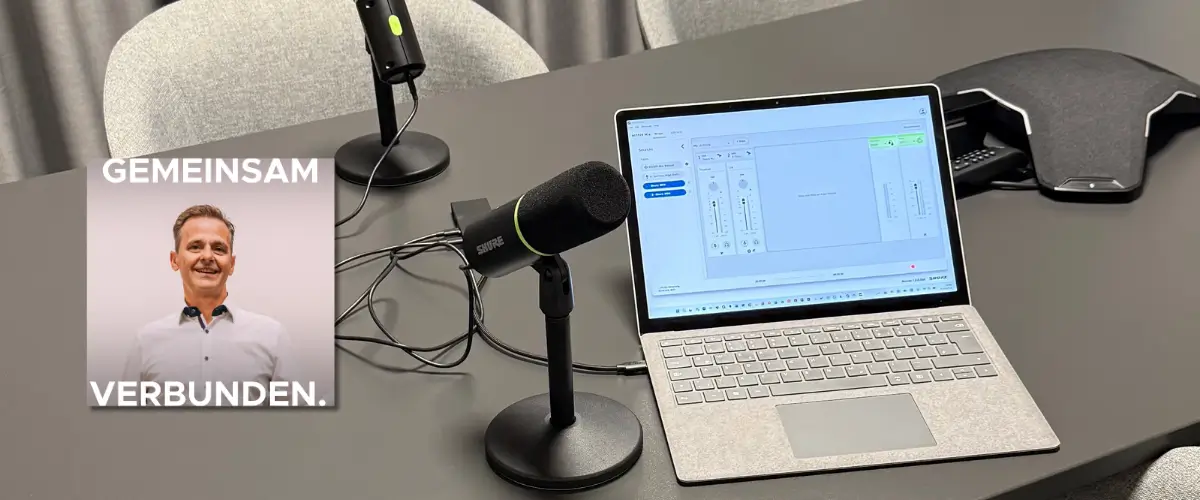 Bild von einem Tisch mit Laptop und zwei Stand Podcast Mikrofonen. Zudem ein Titelbild eines Podcasts.