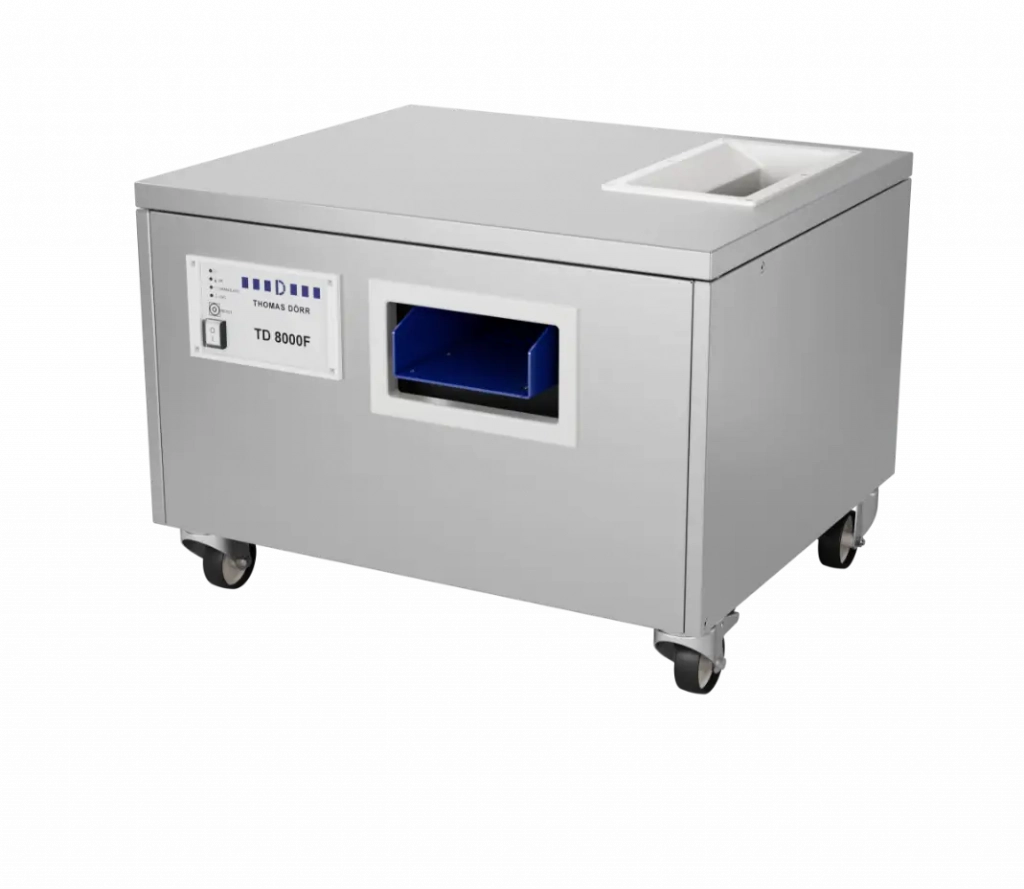 Eine rechteckige, industrielle Edelstahlmaschine auf Rädern mit einem digitalen Bedienfeld, einer rechteckigen Öffnung mit blauem Innenraum und einem weißen, quadratischen Behälter auf der Oberseite.