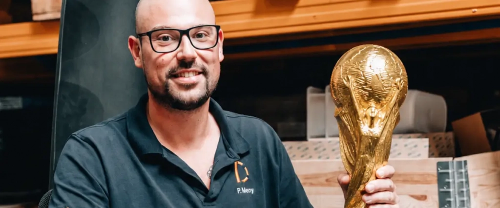 Bild von einer Person mit dem WM Pokal in der Hand.