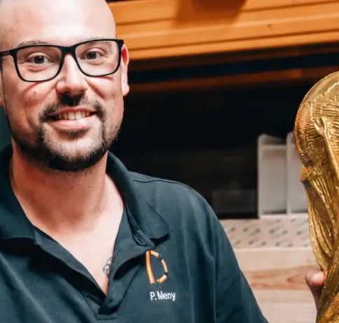 Bild von einer Person mit dem WM Pokal in der Hand. 